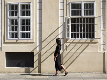 Full length of woman walking on footpath against building
