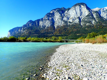 Scenic view of lake and mountains against clear blue sky