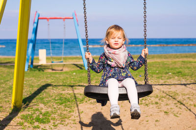 Portrait of girl sitting on swing at playground