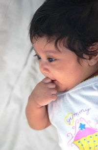 Close-up of baby girl on bed at home