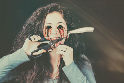 Spooky woman cutting tongue with knife