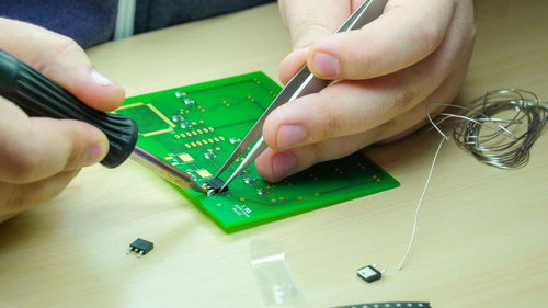 Close-up of person repairing circuit board at table