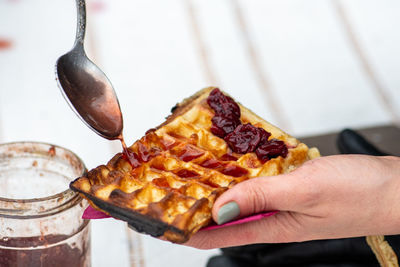 Preparing waffle or waffles with spoon and jam, dish made from leavened batter or dough