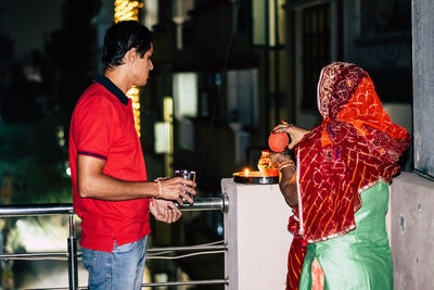 Woman standing with man on terrace during karva chauth at night