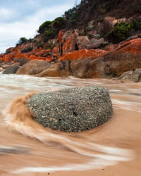 Rock formation on beach against sky