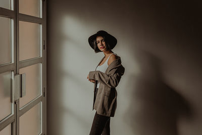 Young woman looking away against wall