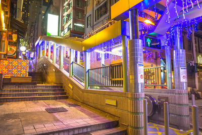 Illuminated street amidst buildings in city at night