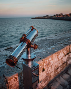 Close-up of coin-operated binoculars by sea against sky