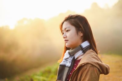 Side view of young woman looking away on field