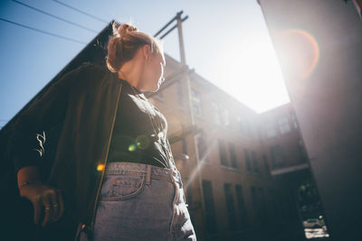 Low angle view of woman standing against sky in city