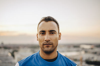 Portrait of confident male athlete against sky during sunset