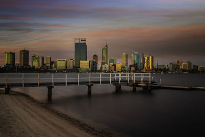 City by sea against sky during sunset