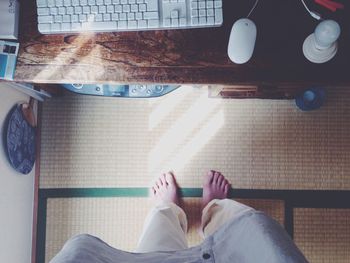 Low section of woman standing on floor by computer keyboard on table