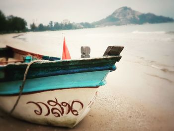 Close-up of boat moored on beach against sky