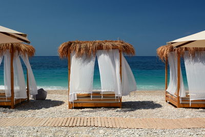Deck chairs on beach against clear sky