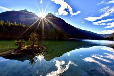 Scenic view of lake and mountains against bright sun