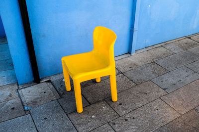 High angle view of yellow chair on sidewalk