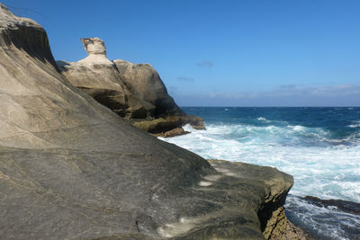 Rock formations by sea against clear sky