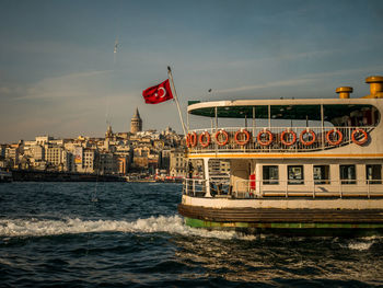 Passenger craft sailing on sea against buildings in city