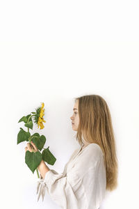 Side view of woman with pink flower against white background