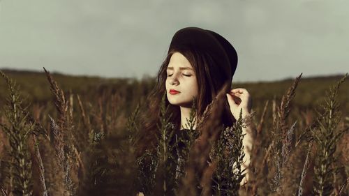 Close-up of young woman in field against sky