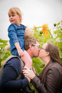 Side view of couple kissing against blurred background, with daughter