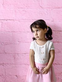 Full length of little girl standing against pink wall