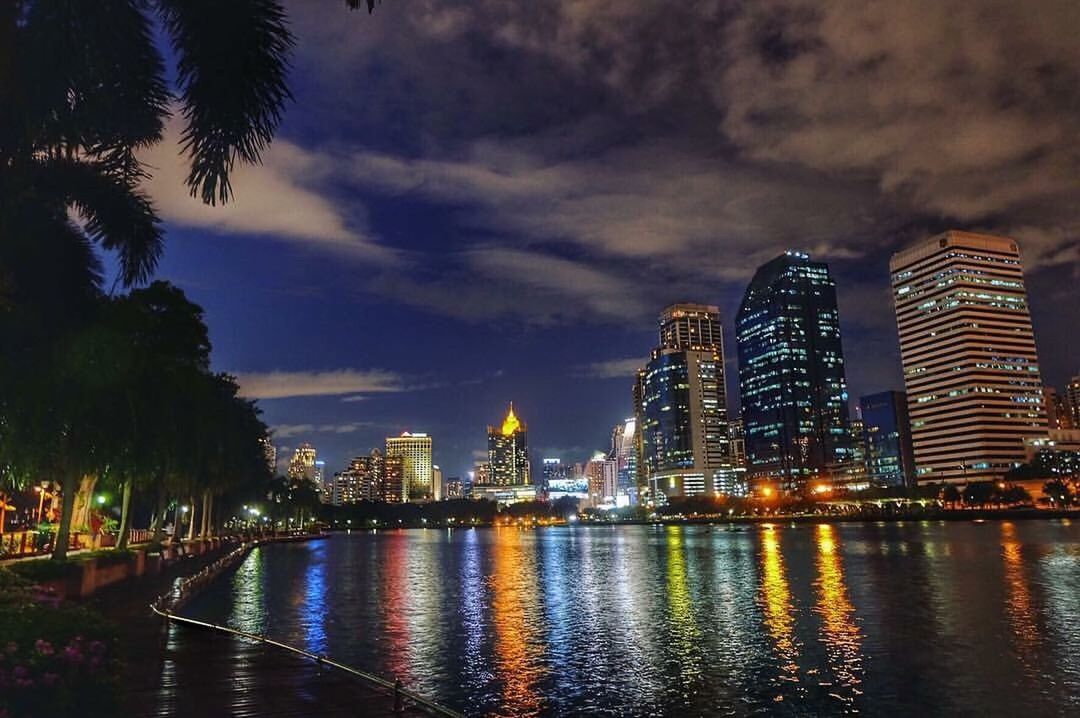 night, illuminated, skyscraper, city, water, urban skyline, reflection, dusk, sky, architecture, modern, cloud - sky, cityscape, travel destinations, business finance and industry, sunset, building exterior, outdoors, tree, downtown district, no people, office building exterior, nightlife