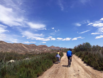 Rear view of men walking on road against sky