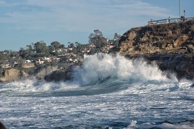 Waves breaking on sea against sky