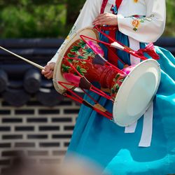 Midsection of woman in traditional clothes banging drum outdoors