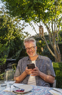 Smiling man in garden using cell phone