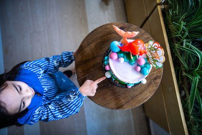 Underwater mermaid cake on the wooden table with child nearby. top view.