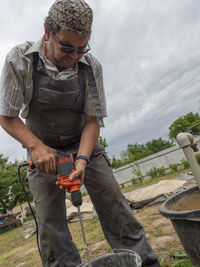 Caucasian man stirs tile glue with a manual electric drill in a bucket