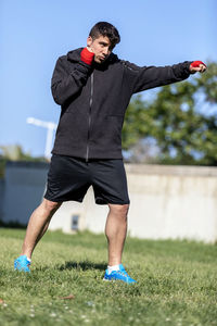 Full length of man exercising while standing on field