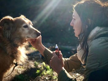 Side view of woman giving medicine to dog