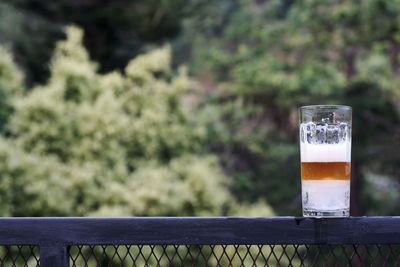 Close-up of beer glass against railing