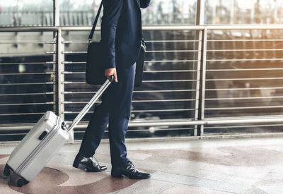 Low section of businessman with suitcase standing in airport