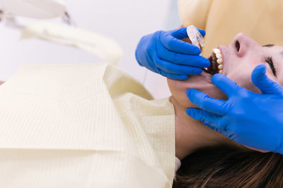 Young female patient with open mouth examining dental inspection