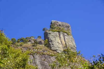 Low angle view of rock formation against clear blue sky