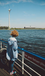 Woman looking at view while standing by railing against sea