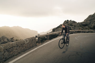 Young man looking at mountains while cycling on road