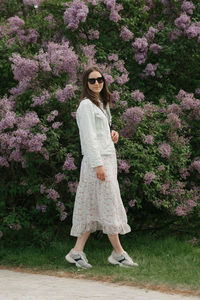 Portrait of young woman standing against trees