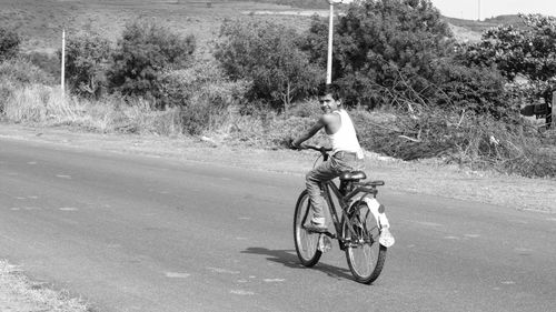 Rear view of man cycling on road