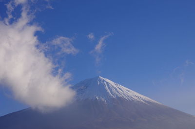 Low angle view of snowcapped mountain against blue sky