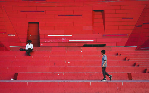 Full length of people walking against red wall