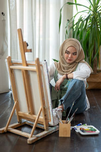 Portrait of young woman sitting on bed at home