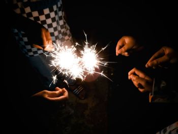 Cropped hand holding sparkler at night