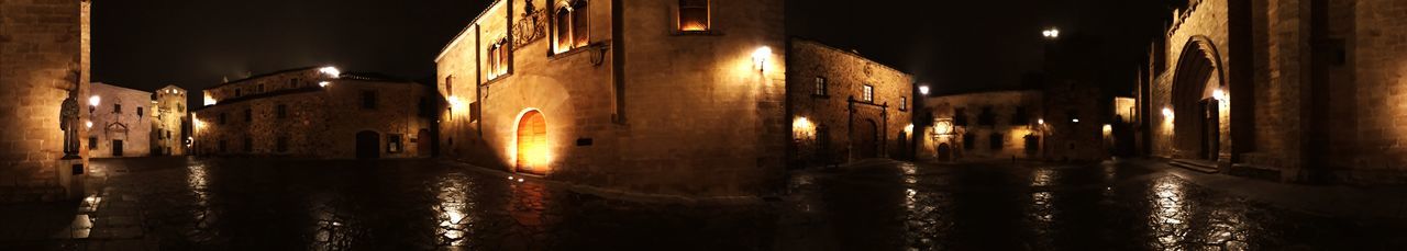 Panoramic shot of illuminated canal amidst buildings at night