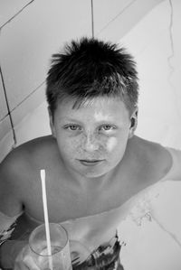 High angle portrait of shirtless boy holding drink while swimming in pool